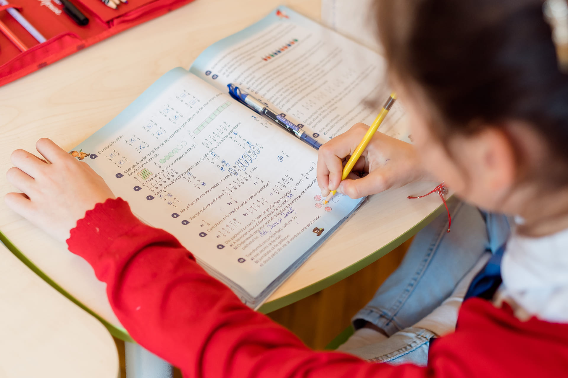 Un copil lucrează la exerciții în caiet, la Fun Academy